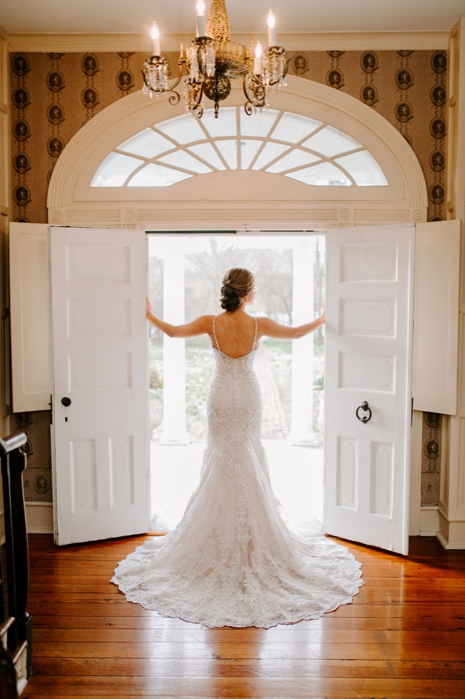 A bride in Spring Haven's open double front doors, under the fanlight and the foyer chandelier